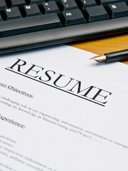 A resume template placed next to a keyboard and pen, illustrating the process of writing a job application document.